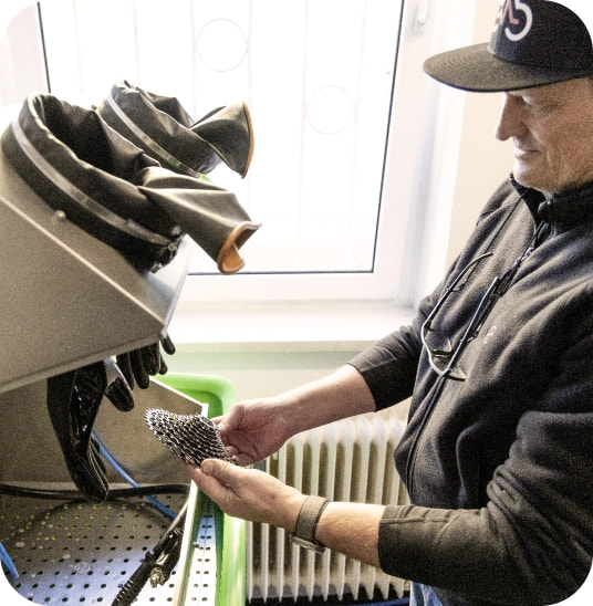 Mitarbeiter reinigt ein Fahrradritzeln im Reinigungsgerät.